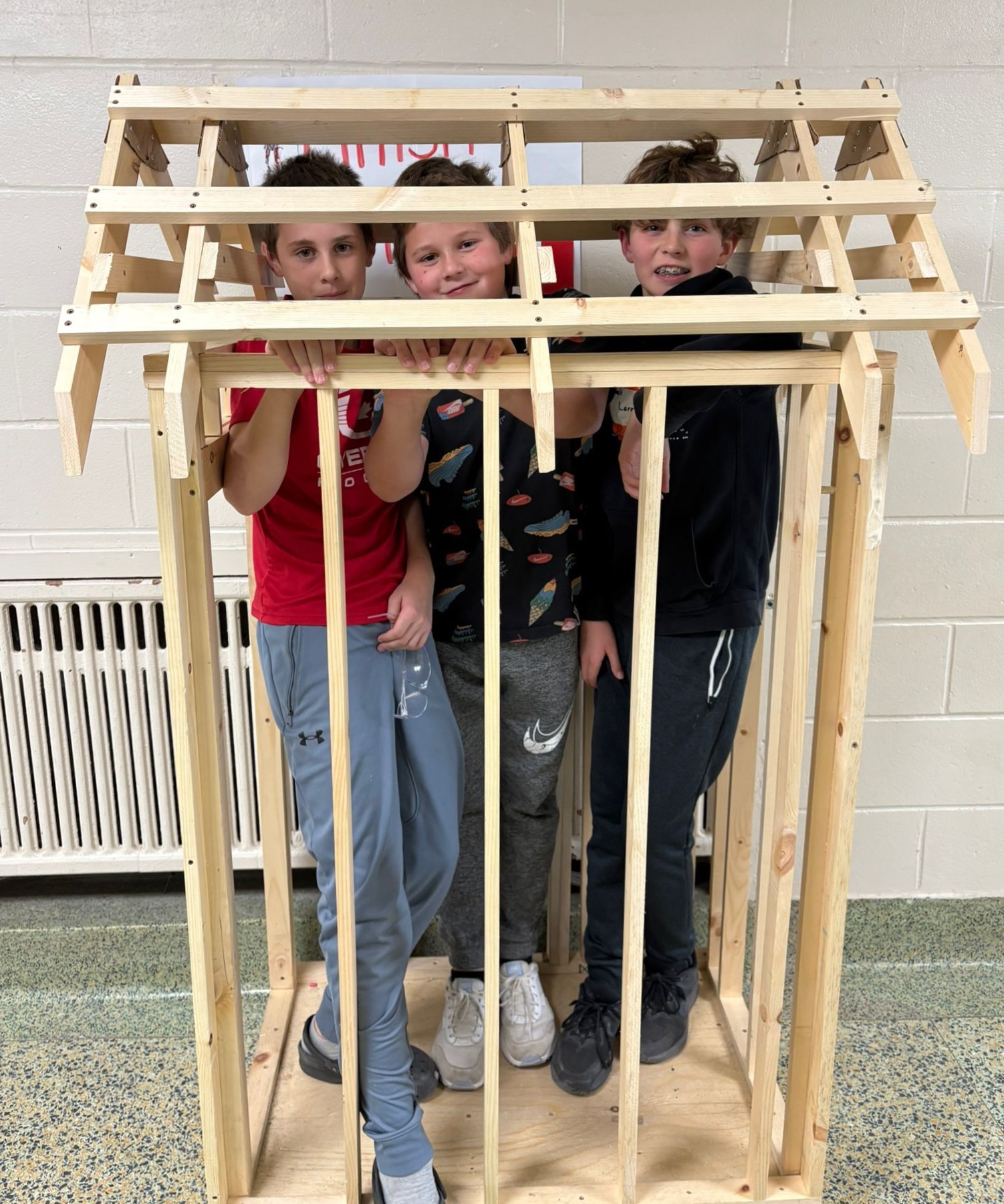 Three Elginburg students standing inside the carpentry structure they built