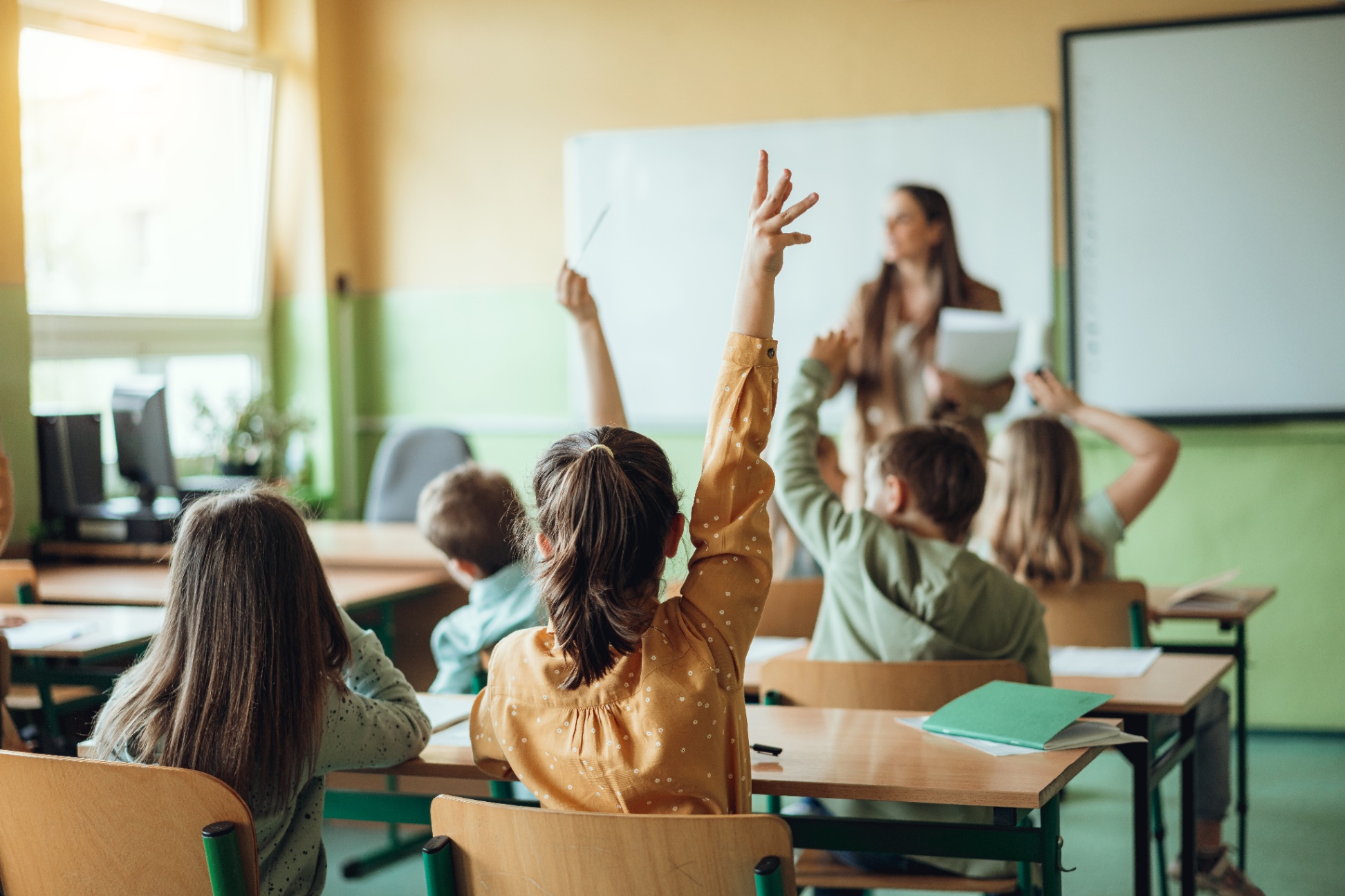 Elementary students sitting at desks listening to a teacher